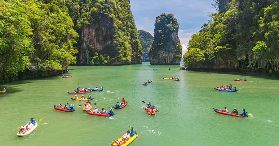 Tourists canoeing through hidden sea caves and lagoons on phang nga bay tour.
