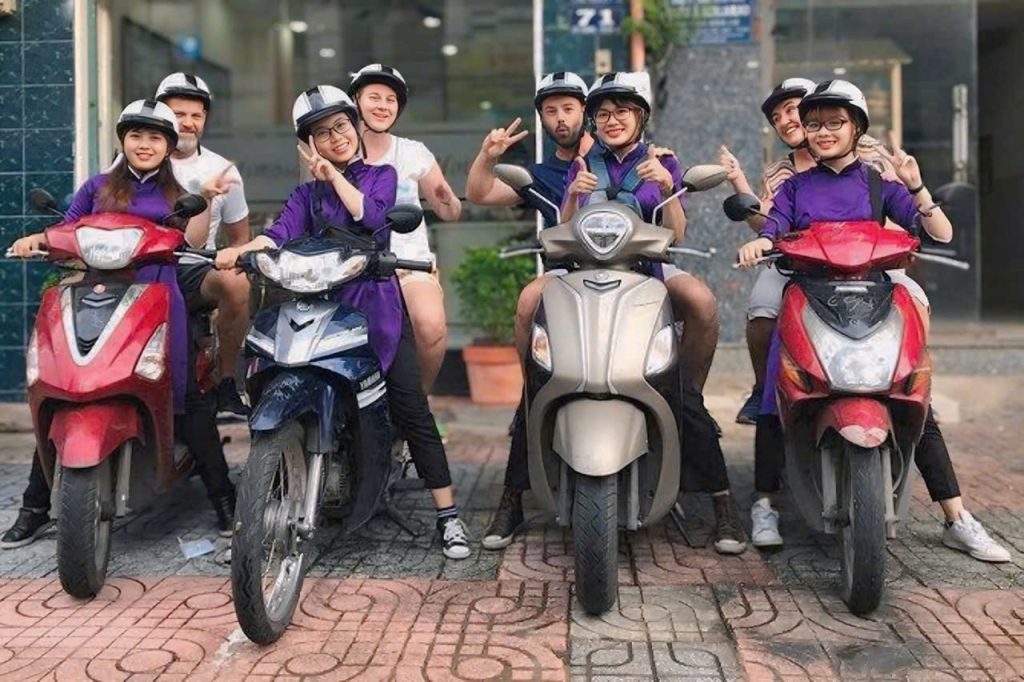 Saigon food tour by scooter: Taste local street food, ride through busy HCMC alleys. Saigon Food Tour by scooter. Local driver and guest riding through HCMC at night.