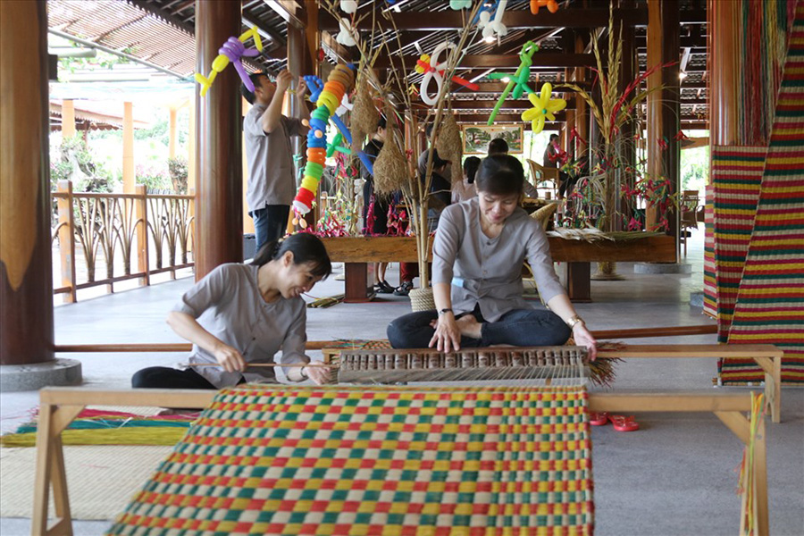 Local artisan weaving a traditional Vietnamese sleeping mat by hand in a Nha Trang craft village on Nha Trang Private City Tour.