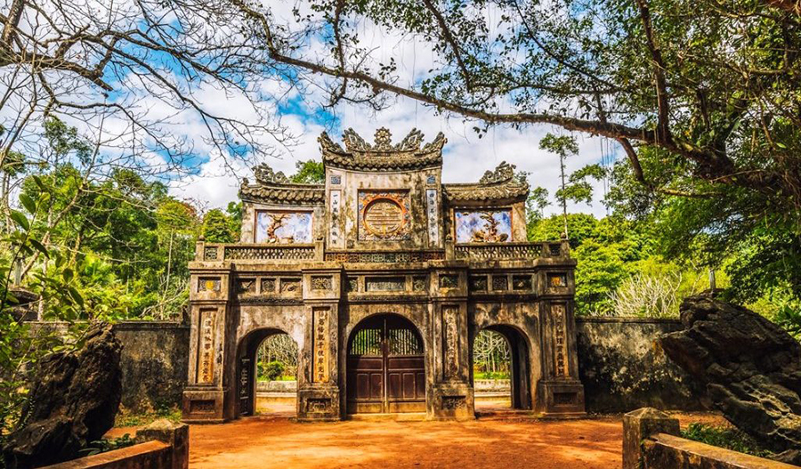 A serene and beautiful moment at the historic Tu Hieu Pagoda in Hue. The main entrance to Tu Hieu Pagoda, surrounded by a lush forest.