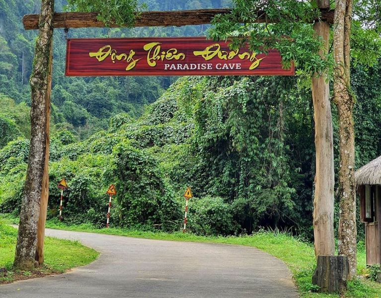 The journey begins! The scenic path to the main entrance of Paradise Cave awaits. A wide, paved path leading to the main entrance of Paradise Cave on a forested hillside.