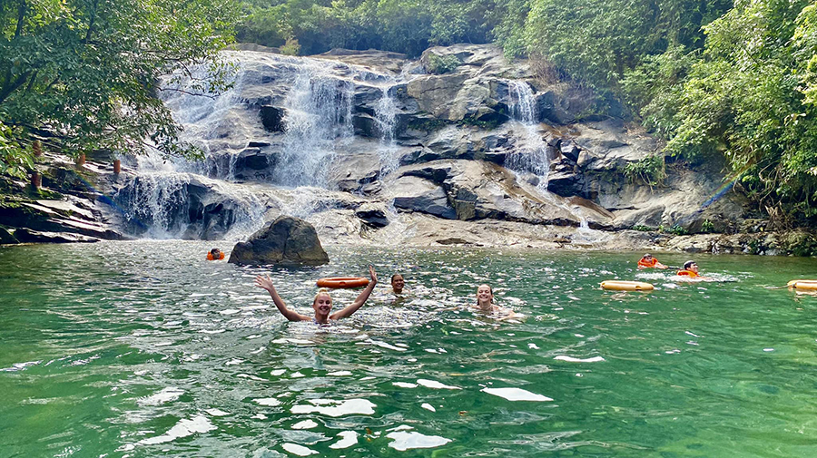 Take a refreshing dip! A perfect stop to cool down at the beautiful Nhi Ho Waterfall. A scenic view of Nhi Ho Waterfall with clear water flowing over large mossy rocks.