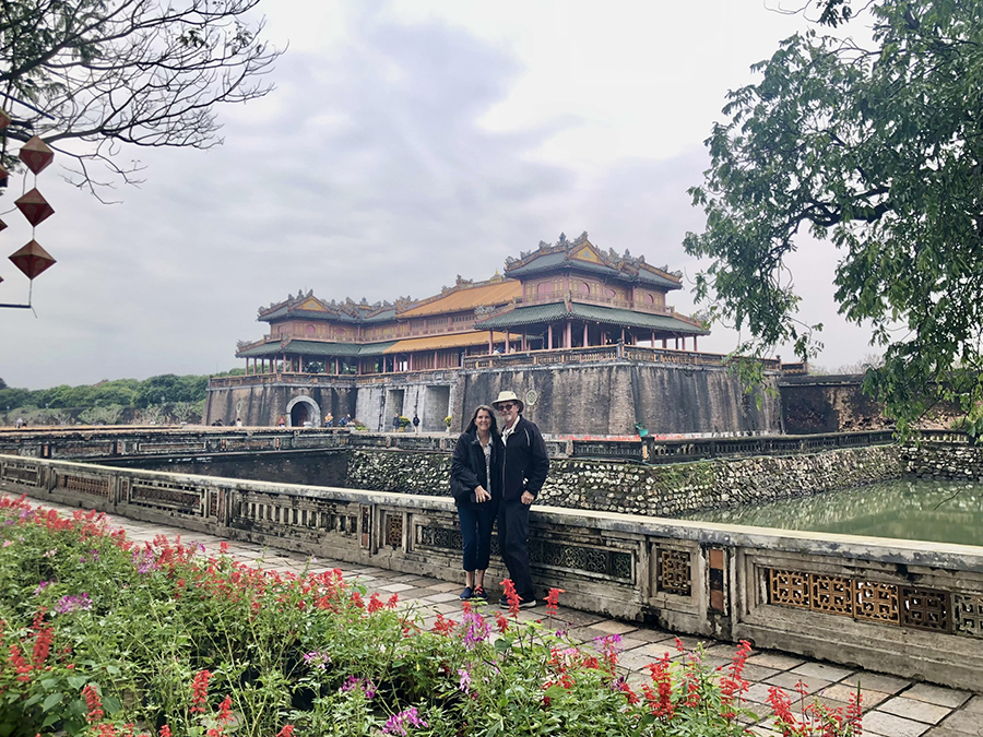 An American couple enjoys a private tour, exploring Hue’s historic and cultural landmarks with their guide. A smiling American couple with a local guide on their Hue private tour, standing in front of a historic landmark.