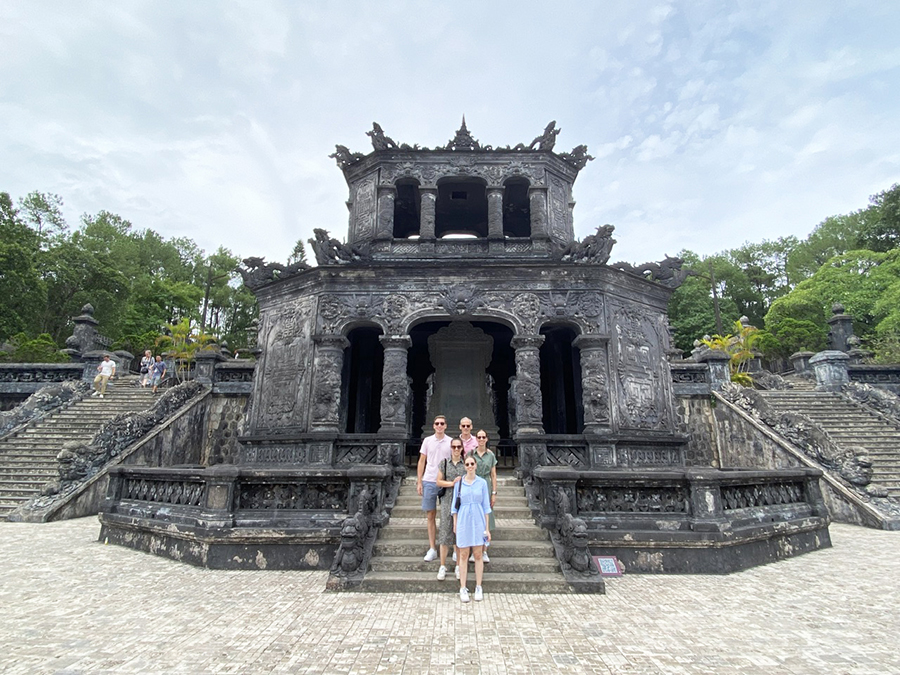A group of tourists posing for a photo in front of the grand mausoleum of Khai Dinh. A small group of customers stand at the impressive entrance of the Khai Dinh Tomb.